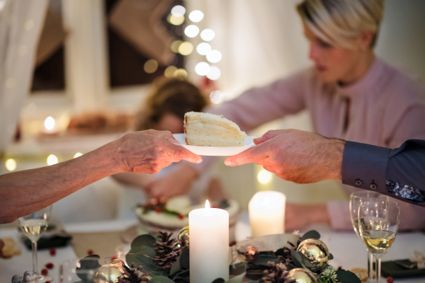 Multi-generation family indoors celebrating Christmas together, passing cake.