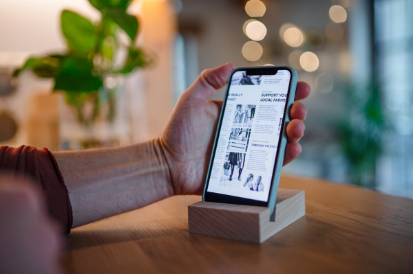 A smartphone in wooden stand holder on table indoors at home or on office.