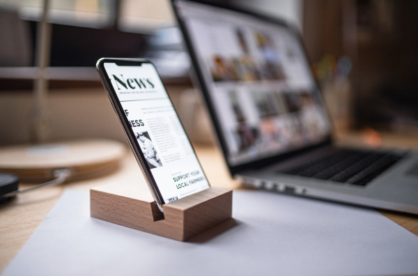 A smartphone in wooden stand holder on table indoors at home or on office.