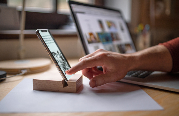 A smartphone in wooden stand holder on table indoors at home or on office.