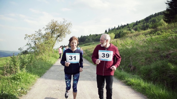 A large group of active multi generation people running a race competition in nature. Slow motion.