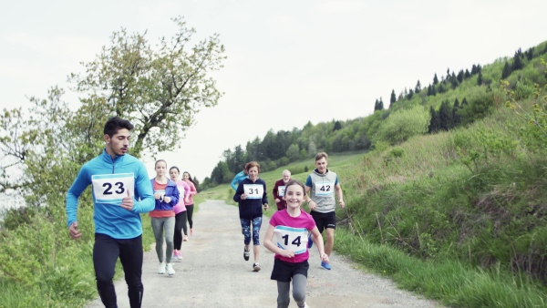 A large group of active multi generation people running a race competition in nature.