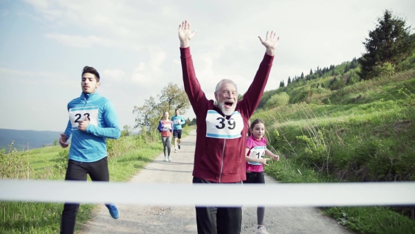 A large group of active multi generation people running a race competition in nature. Slow motion.