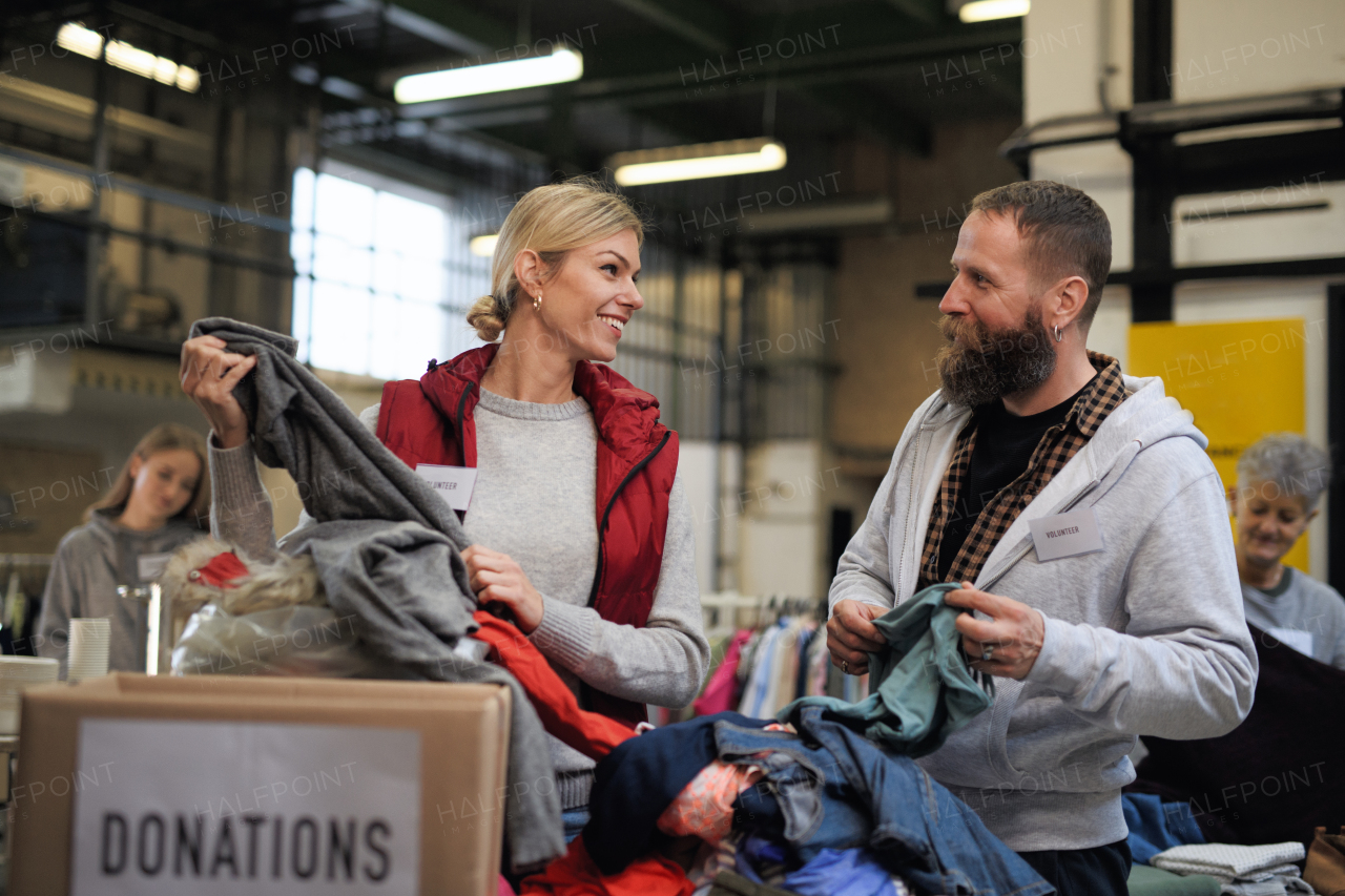 Portrait of volunteers sorting out donated clothes in community charity donation center.