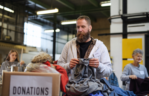 Portrait of volunteers sorting out donated clothes in community charity donation center.