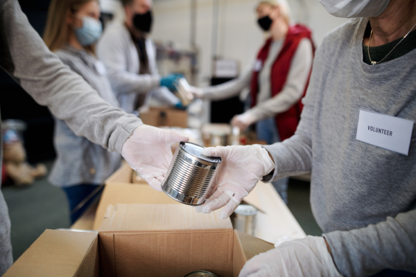 Group of volunteers working in community charity donation center, food bank and coronavirus concept.