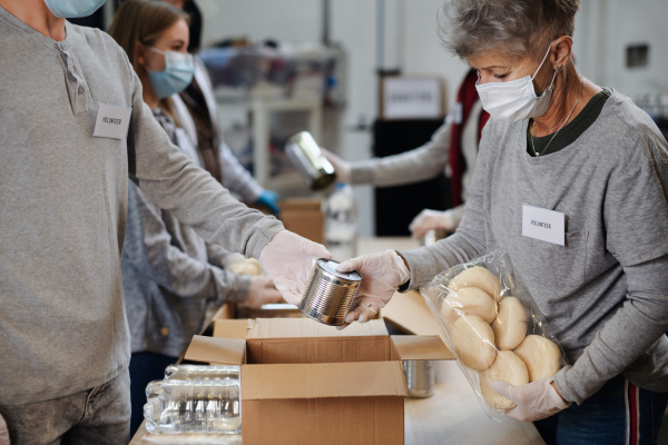 Group of volunteers working in community charity donation center, food bank and coronavirus concept.