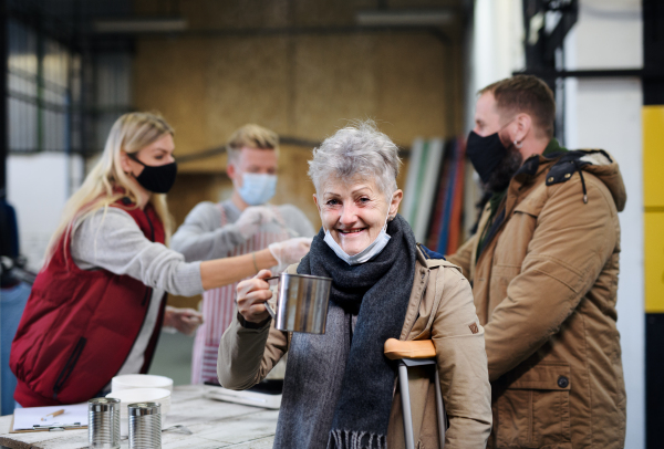 Volunteers serving hot soup for ill and homeless in community charity donation center, food bank and coronavirus concept.