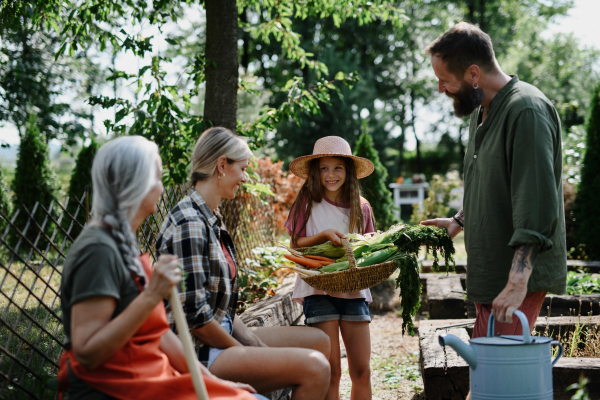 A happy farmer family looking at their harvest outdoors in garden.