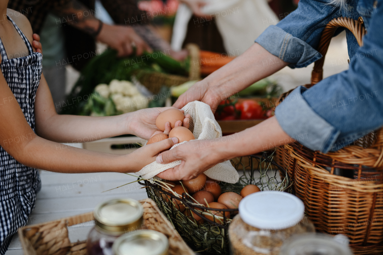 A close up of little girl buying organic eggs outdoors at local farmers market.