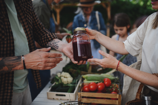 A close up of woman buying organic juice outdoors at local farmers market.