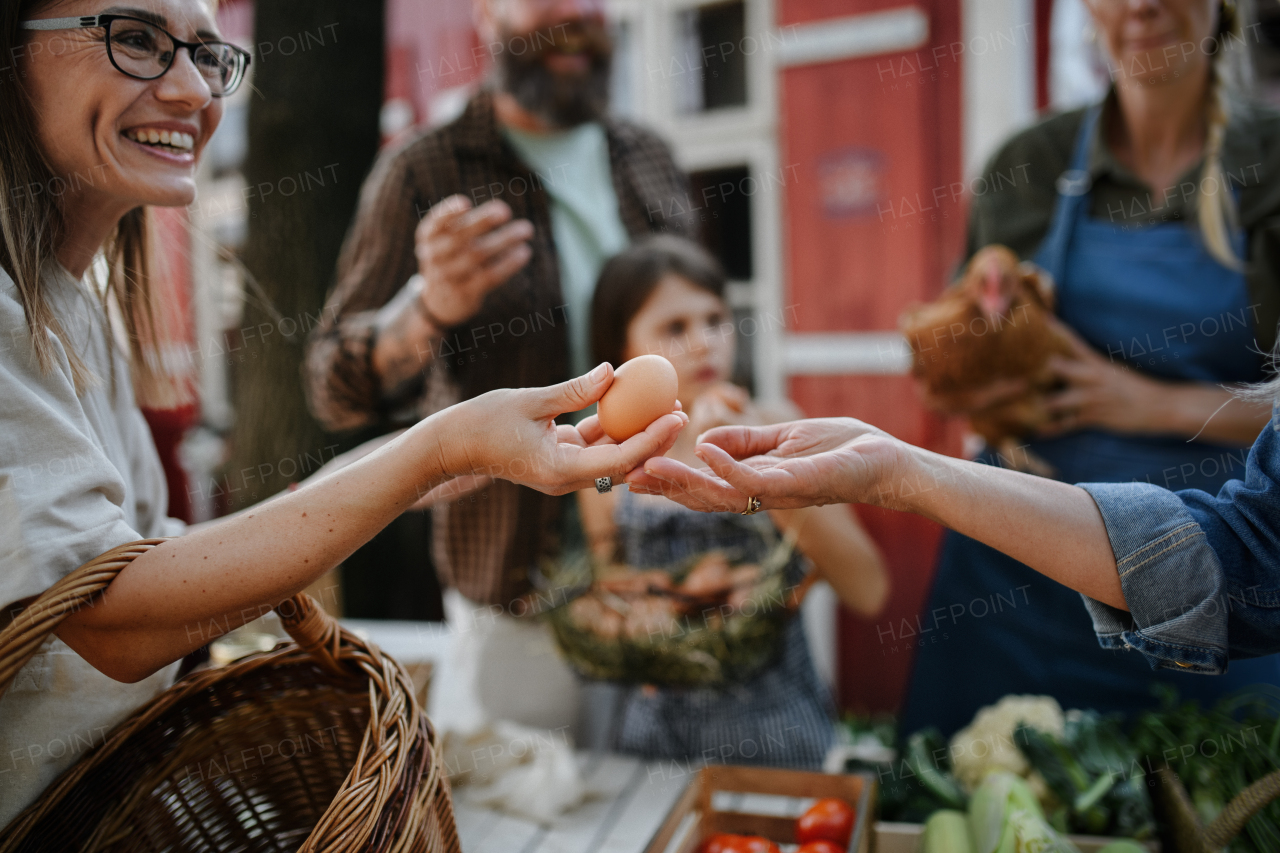 A close up of woman buying organic eggs outdoors at local farmers market.