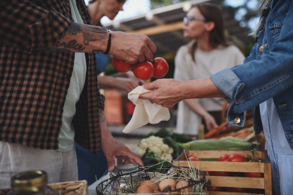 A close up of woman buying organic vegetables outdoors at local farmers market.