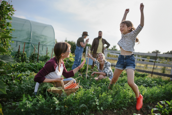 Happy young and old farmers or gardeners working outdoors at a community farm.