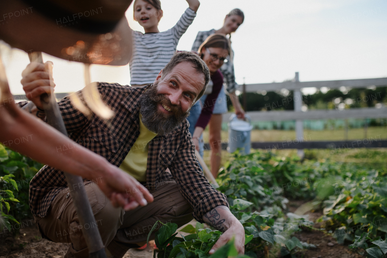 Happy young and old farmers or gardeners working outdoors at a community farm.