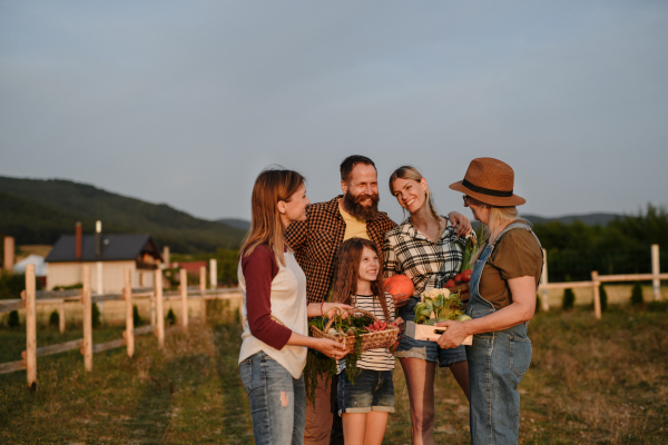 A happy farmer family holding their harvest outdoors in garden.