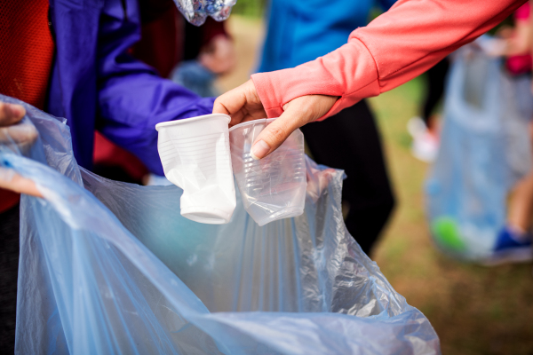 A midsection of group of fit young people picking up litter in nature, a plogging concept.