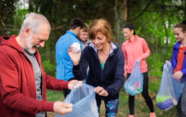 A roup of fit young people picking up litter in nature, a plogging concept.