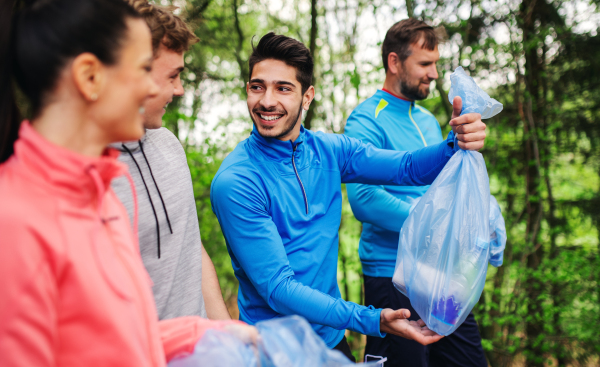 A group of fit young people picking up litter in nature, a plogging concept.