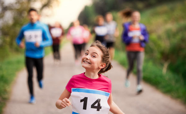 A large group of active multi generation people running a race competition in nature.