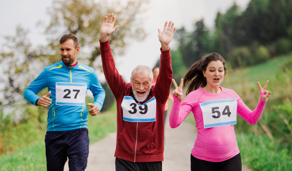 A large group of active multi generation people running a race competition in nature.