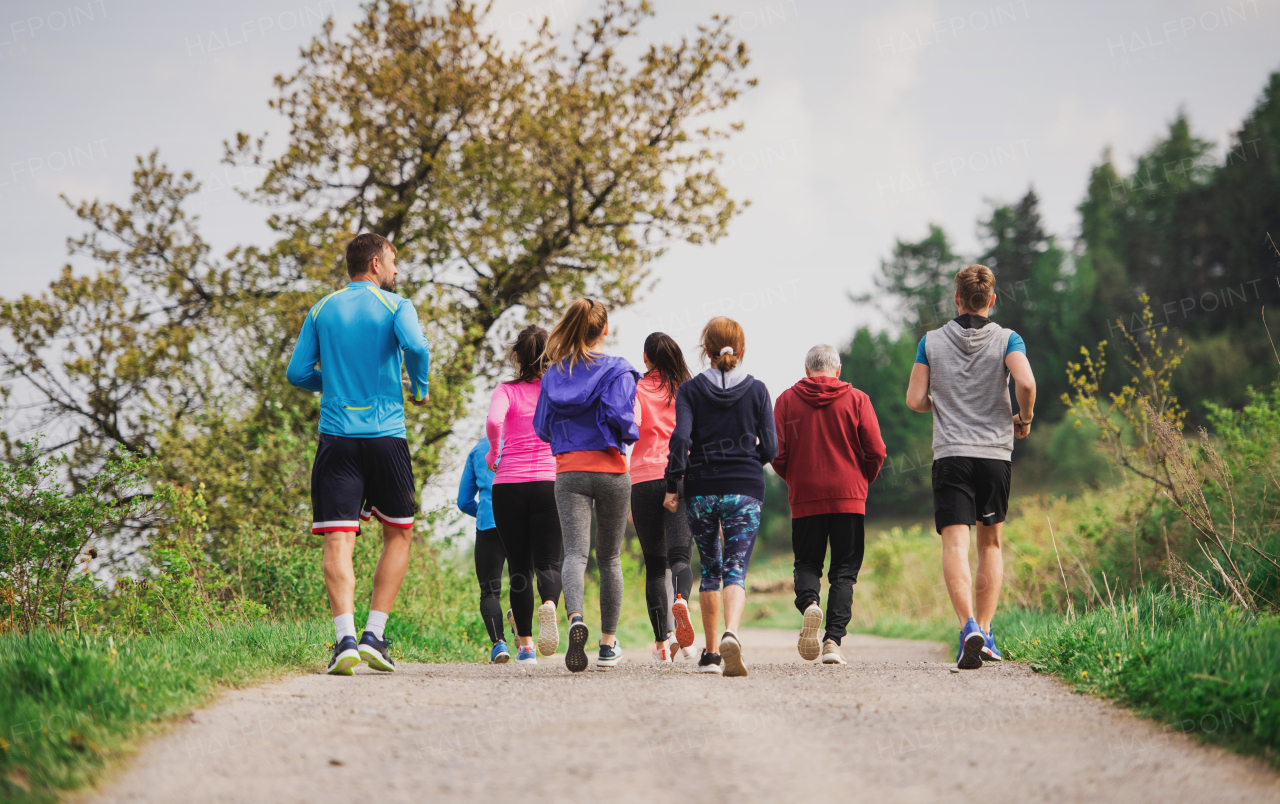 Rear view of group of active multi generation people running a race competition in nature.