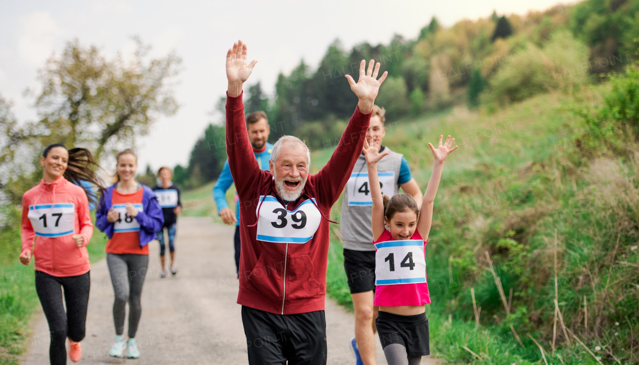 A large group of active multi generation people running a race competition in nature.