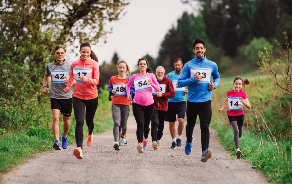 A large group of active multi generation people running a race competition in nature.