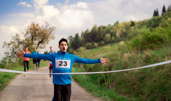 A man runner crossing finish line in a race competition in nature.