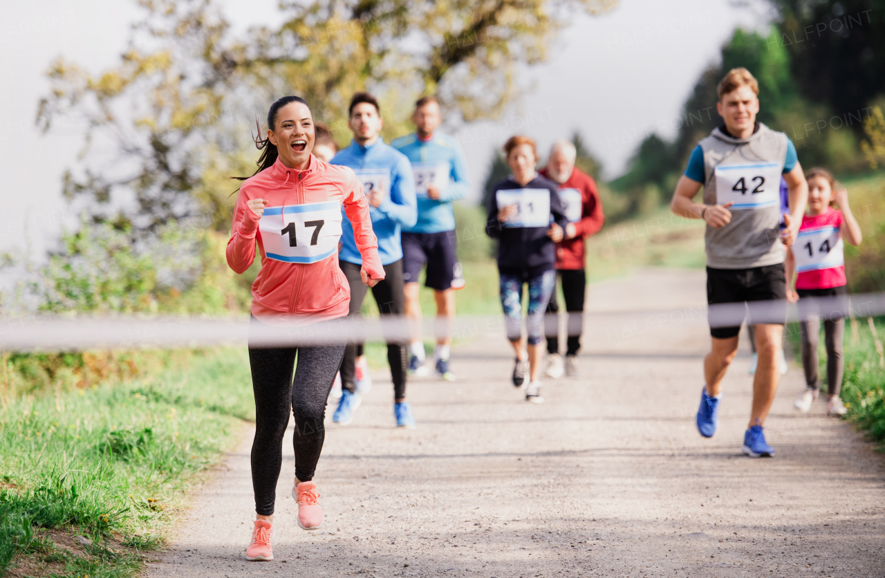 A large group of active multi generation people running a race competition in nature.