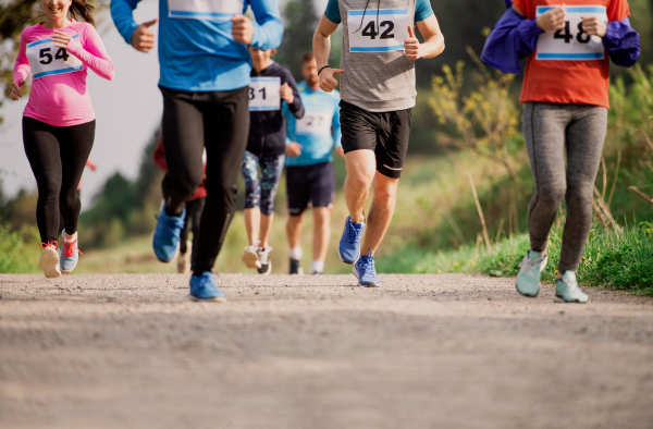 A midsection of large group of people running a race competition in nature.