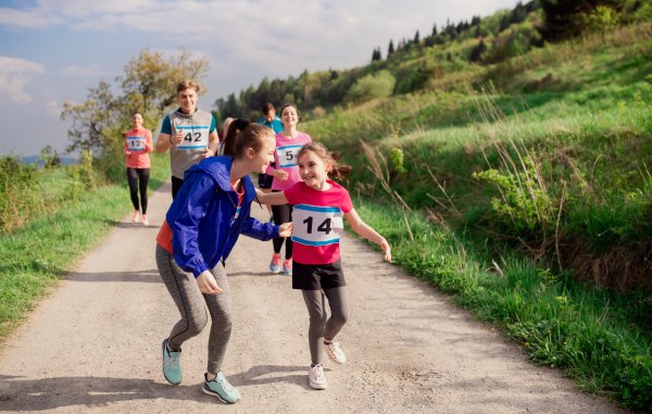 A large group of active multi generation people running a race competition in nature.