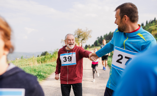 A large group of active multi generation people running a race competition in nature.