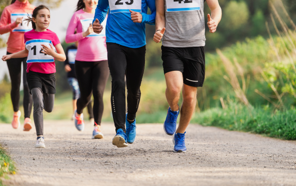 A midsection of large group of people running a race competition in nature.