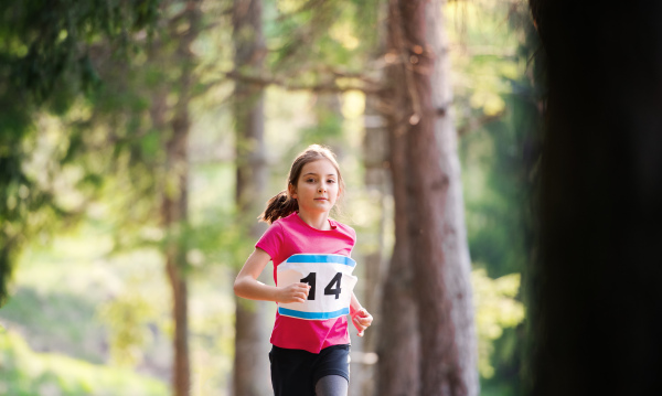 A front view of small child running a race competition in nature. Copy space.