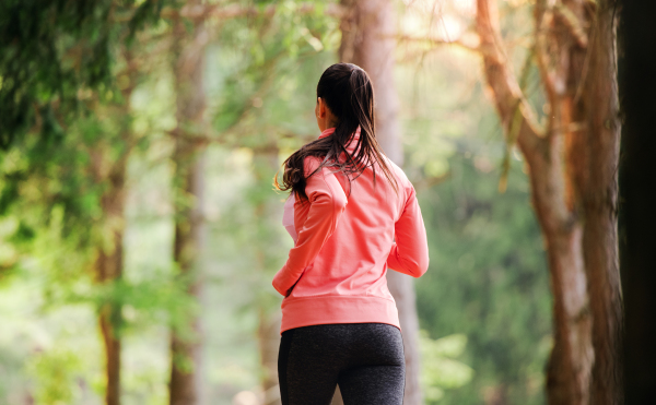 A rear view of young woman running a race competition in nature. Copy space.