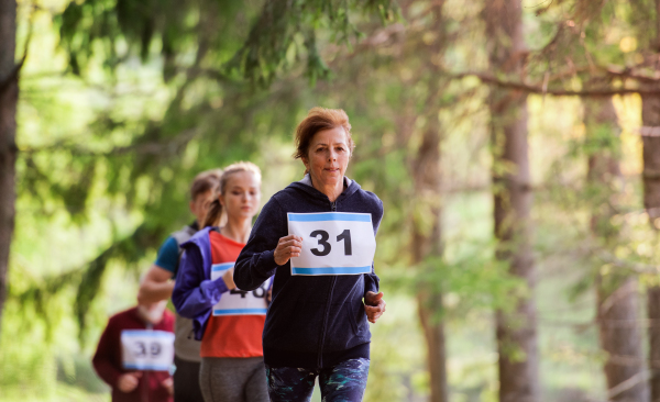 A large group of active multi generation people running a race competition in nature.