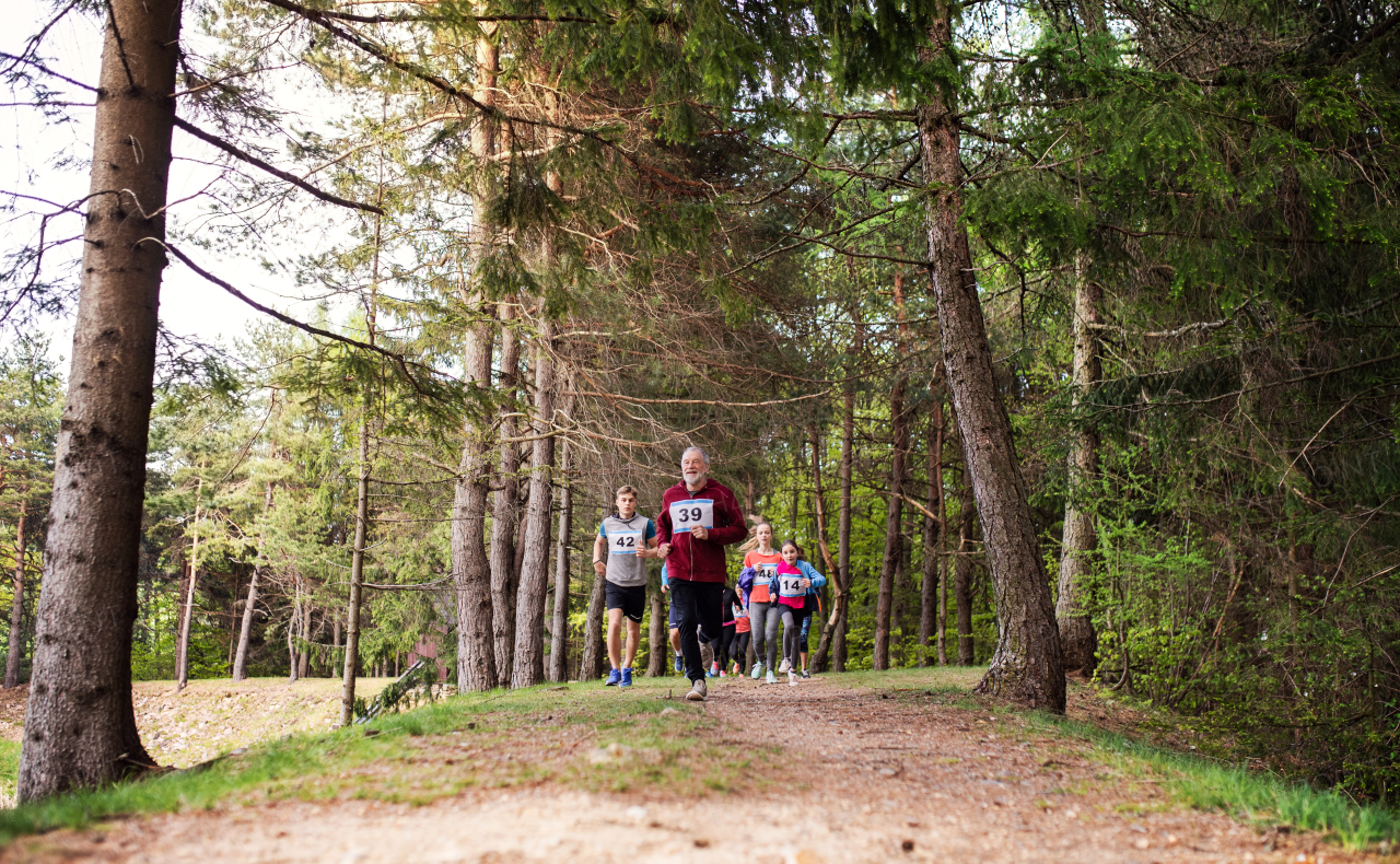 A large group of active multi generation people running a race competition in nature.