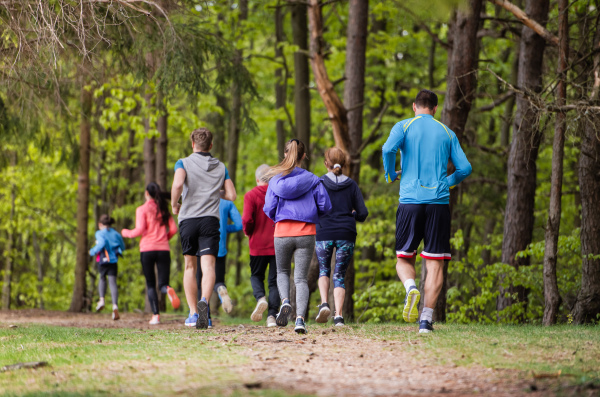 Rear view of large group of multi generation people running a race competition in nature.