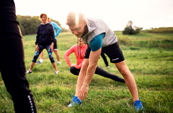 A large group of fit and active people doing exercise in nature.