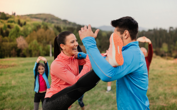 A large group of fit and active people doing exercise in nature.