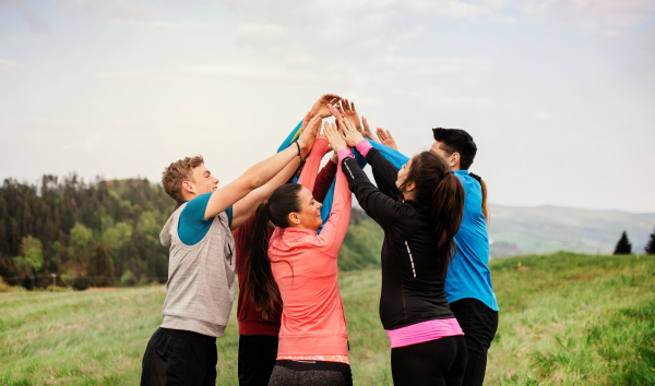 A large group of fit and active people resting after doing exercise in nature.