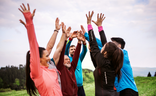 A large group of fit and active people resting after doing exercise in nature.