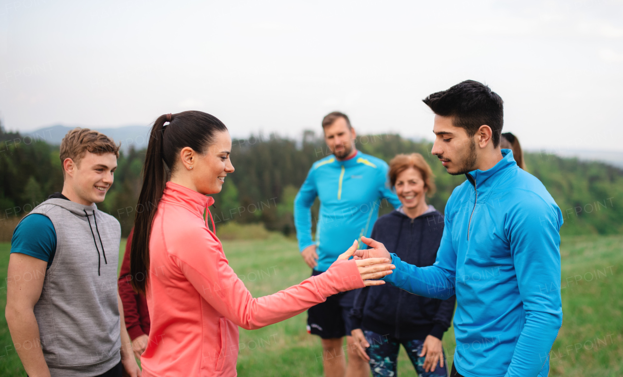 A large group of fit and active people resting after doing exercise in nature.