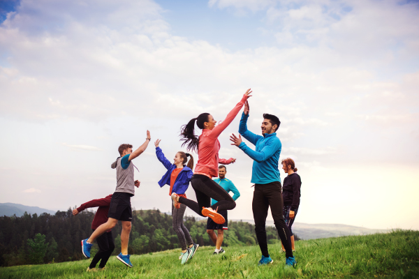 A large group of fit and active people jumping after doing exercise in nature.