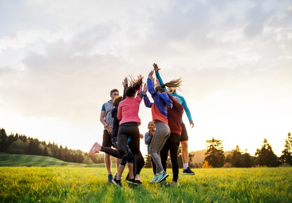 A large group of fit and active people jumping after doing exercise in nature.