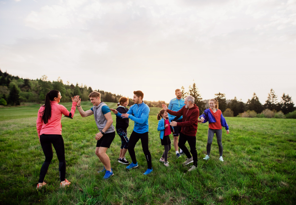 A large group of fit and active people resting after doing exercise in nature.