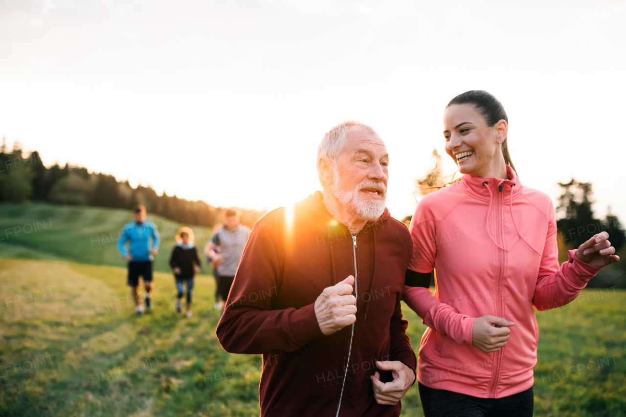 A large group of people cross country running in nature at sunset.