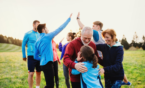 A large group of fit and active people resting after doing exercise in nature.