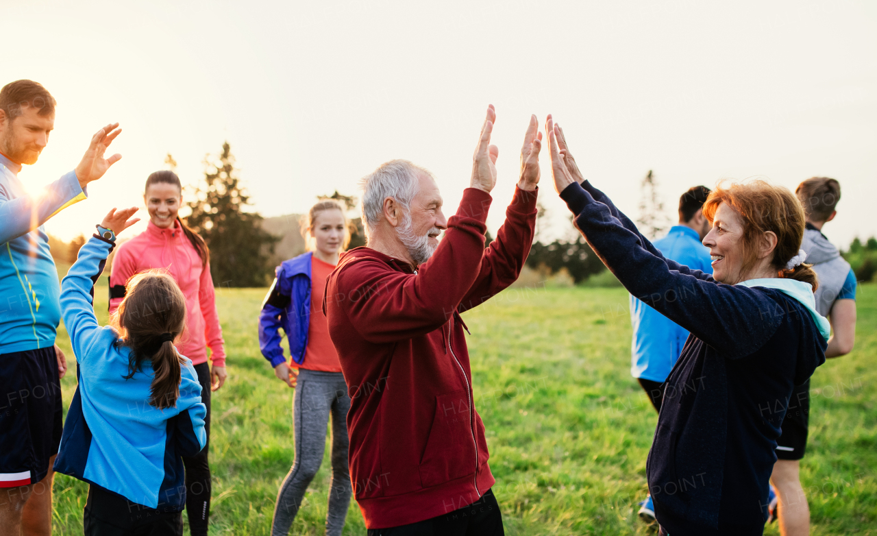 A large group of fit and active people resting after doing exercise in nature.